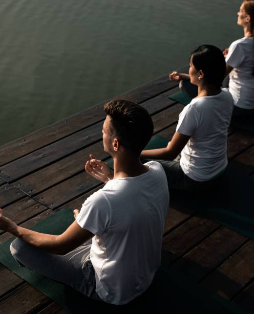 Group of people doing yoga exercises by the lake at sunset. Group of people doing yoga exercises by the lake at sunset.