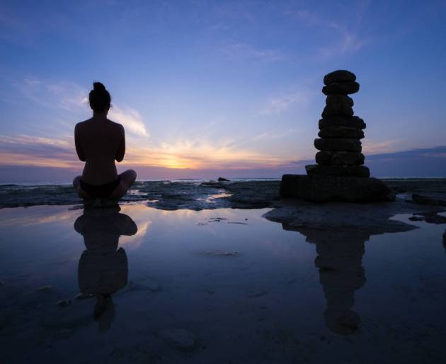 Silhouette of a girl meditated against beautiful sunset on the sea A Silhouette of a girl meditated against beautiful sunset on the sea